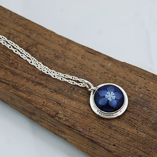 Small pendant kiln fused blue and silver dichroic mica columbine on blue dichroic glass in handcrafted sterling silver setting with rope chain