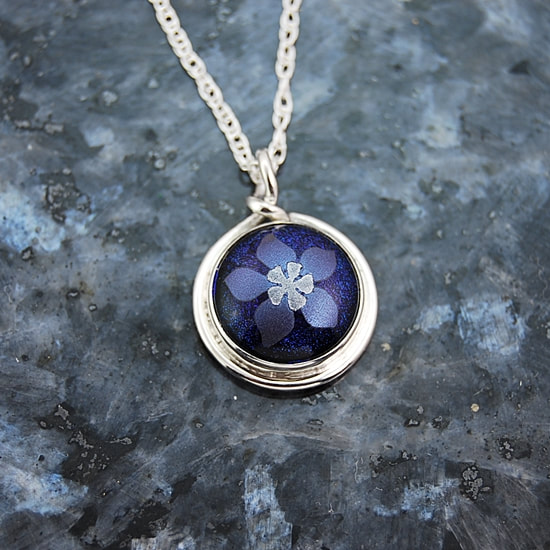 Small pendant kiln fused blue and silver dichroic mica columbine on blue dichroic glass handcrafted 17mm sterling silver bezel setting with round wire trim and leaf cutouts on back sterling and silver rope chain