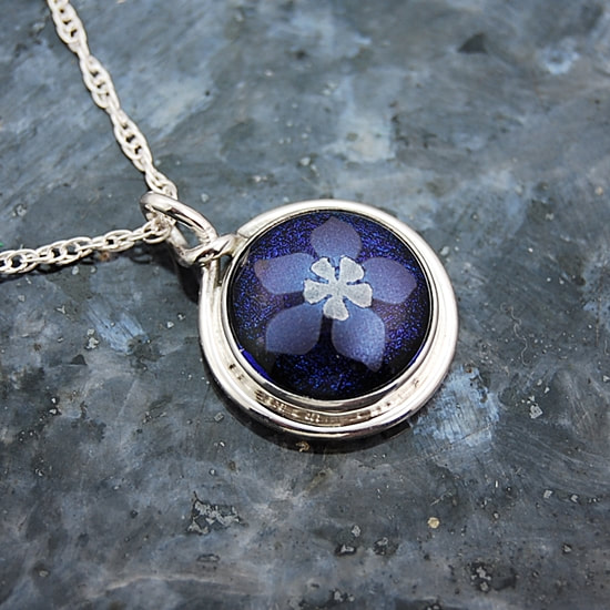 Small pendant kiln fused blue and silver dichroic mica columbine on blue dichroic glass handcrafted 17mm sterling silver bezel setting with round wire trim and leaf cutouts on the back sterling silver rope chain